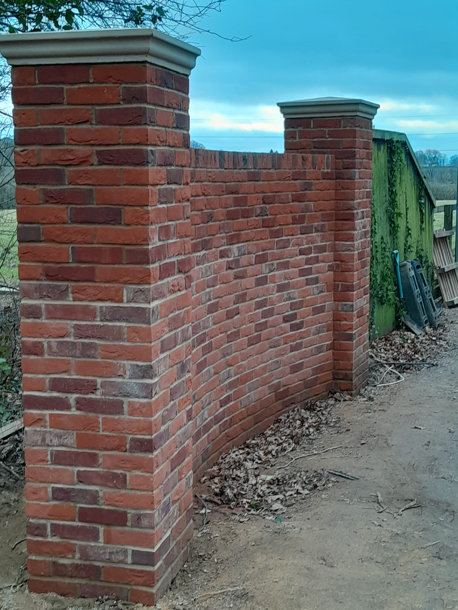 Curved brick boundary wall with coping